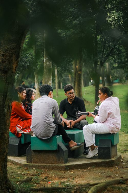 Free Group of friends enjoying a casual meeting outdoors in Dhaka's lush park setting. Stock Photo