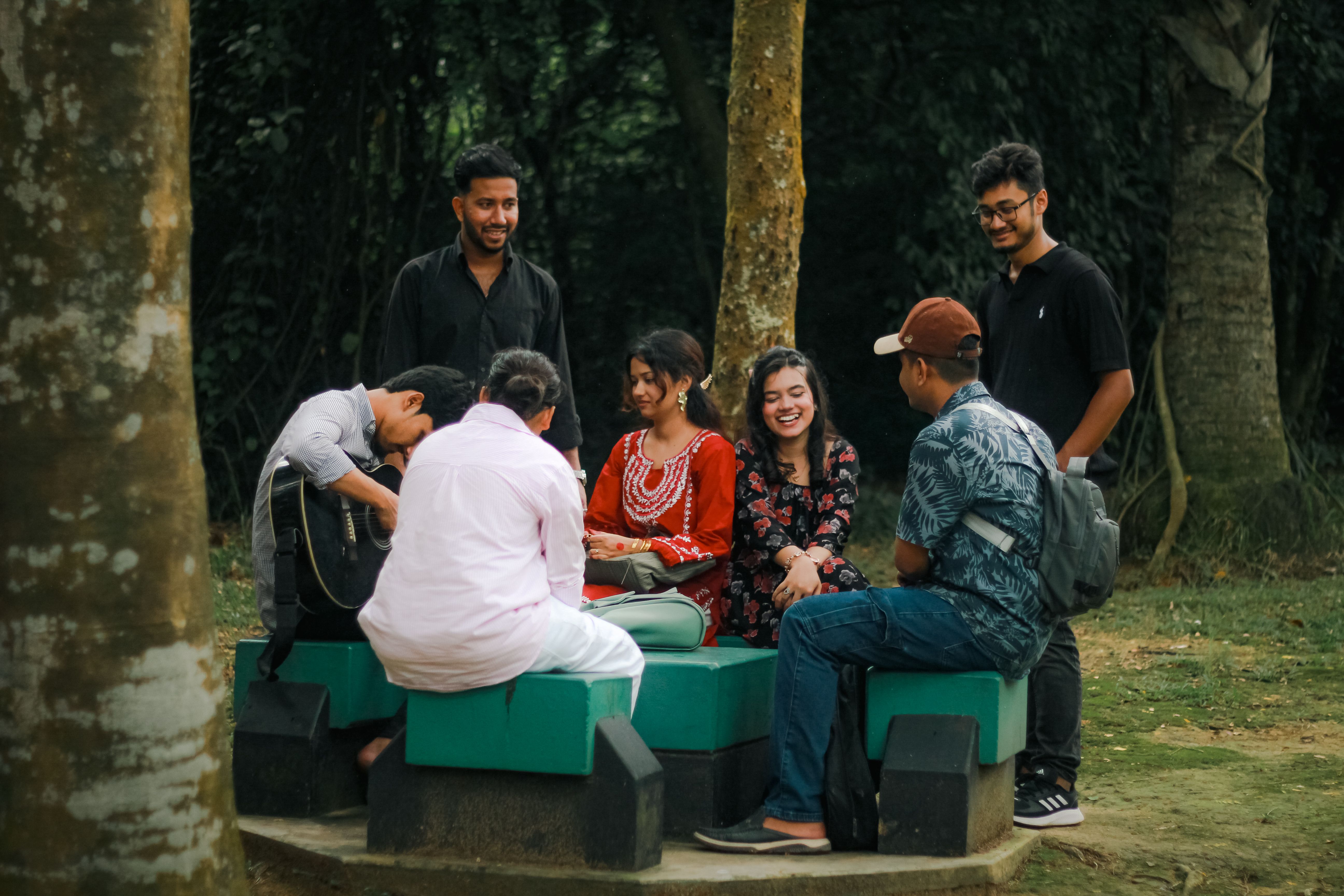 A group of young adults sharing a joyful moment outdoors in a park in Dhaka, Bangladesh.