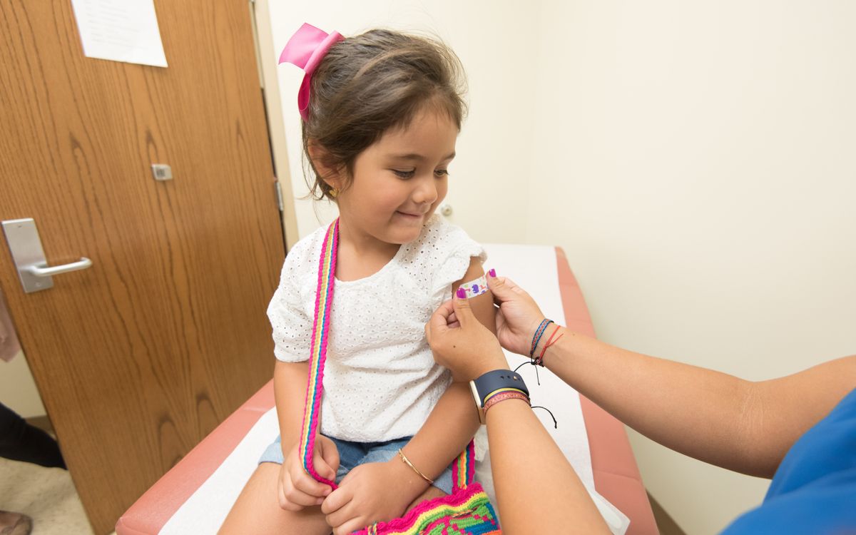 A cheerful young girl receives a band-aid after a vaccination at a clinic.