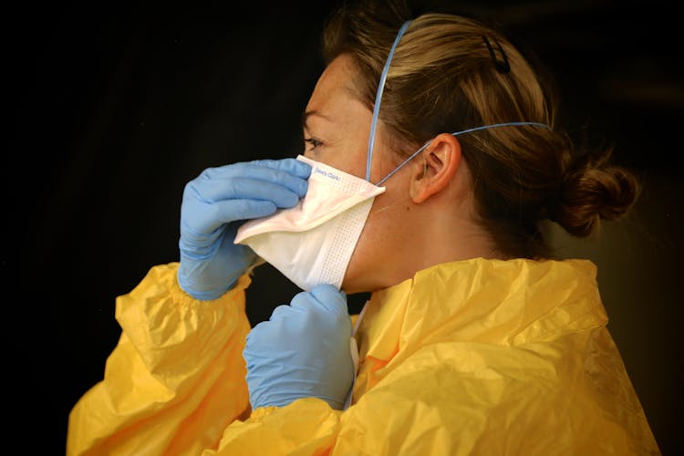 Woman In Yellow Protective Suit Wearing White Face Mask