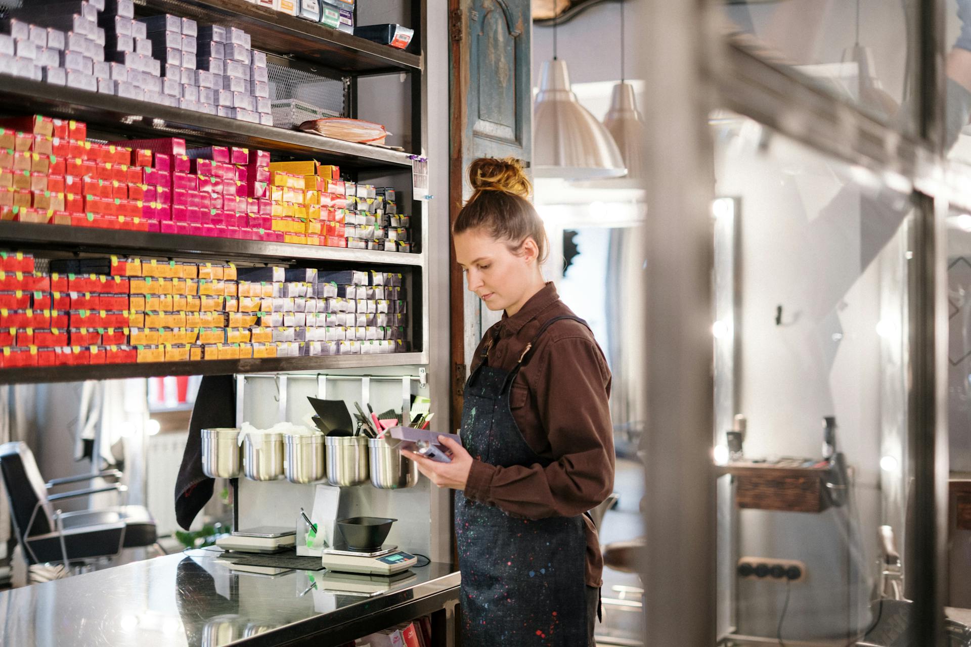 A hairdresser organizing vibrant hair dye boxes in a modern beauty salon.