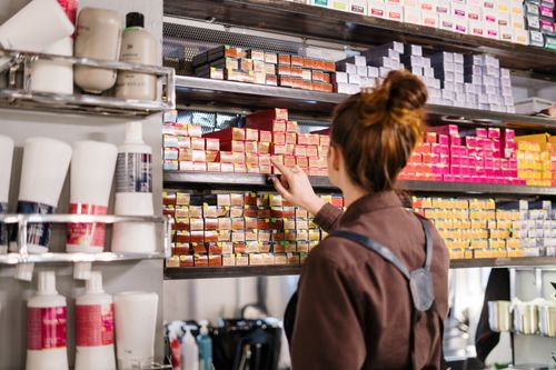 Free A hairstylist organizing vibrant hair color boxes on a shelf in a beauty salon. Stock Photo