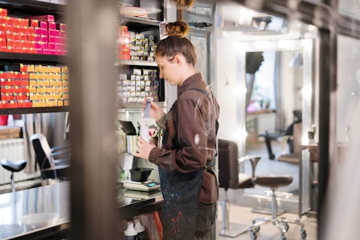 Hairdresser mixing hair color in a modern salon setting with colorful dye boxes.