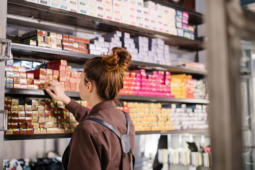 Free Hairdresser choosing hair dye from organized shelves in a beauty salon. Stock Photo