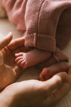Close-up of a baby's feet surrounded by gentle hands, showcasing tenderness and care.