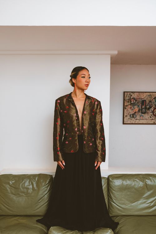 Free Elegant woman in a floral jacket and long skirt posing indoors with minimalistic decor. Stock Photo