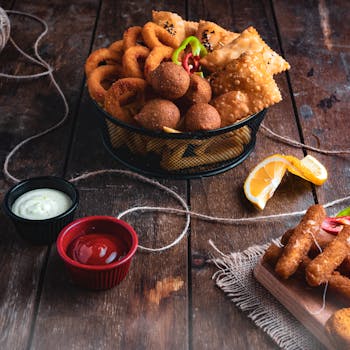 A delicious array of fried snacks with sauces on a rustic wooden table, perfect for a party or gathering.