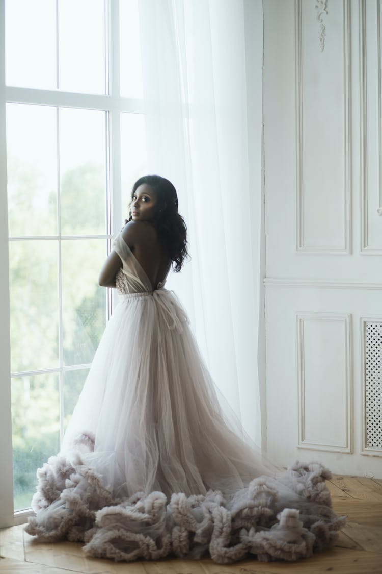 Woman In White Wedding Dress Standing Near The Window