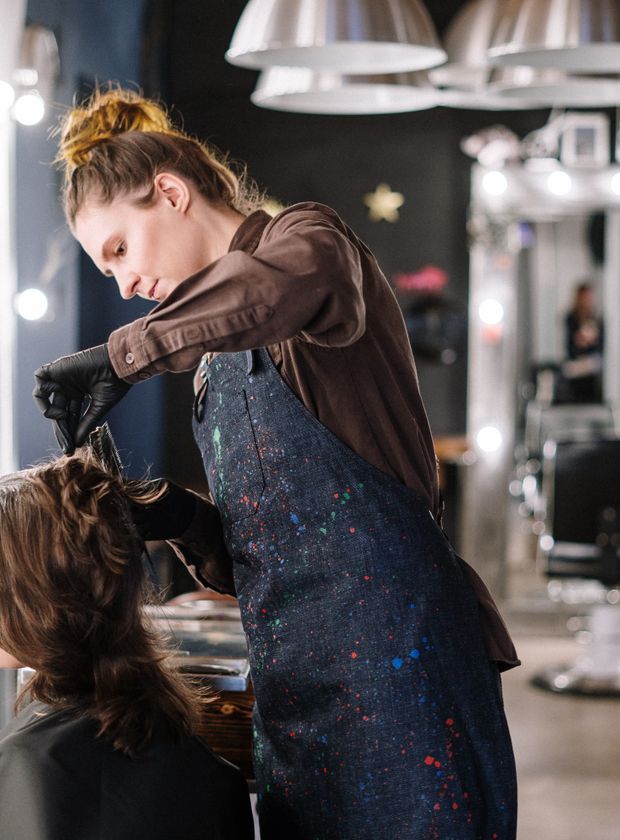 Female stylist applying hair colour section by section