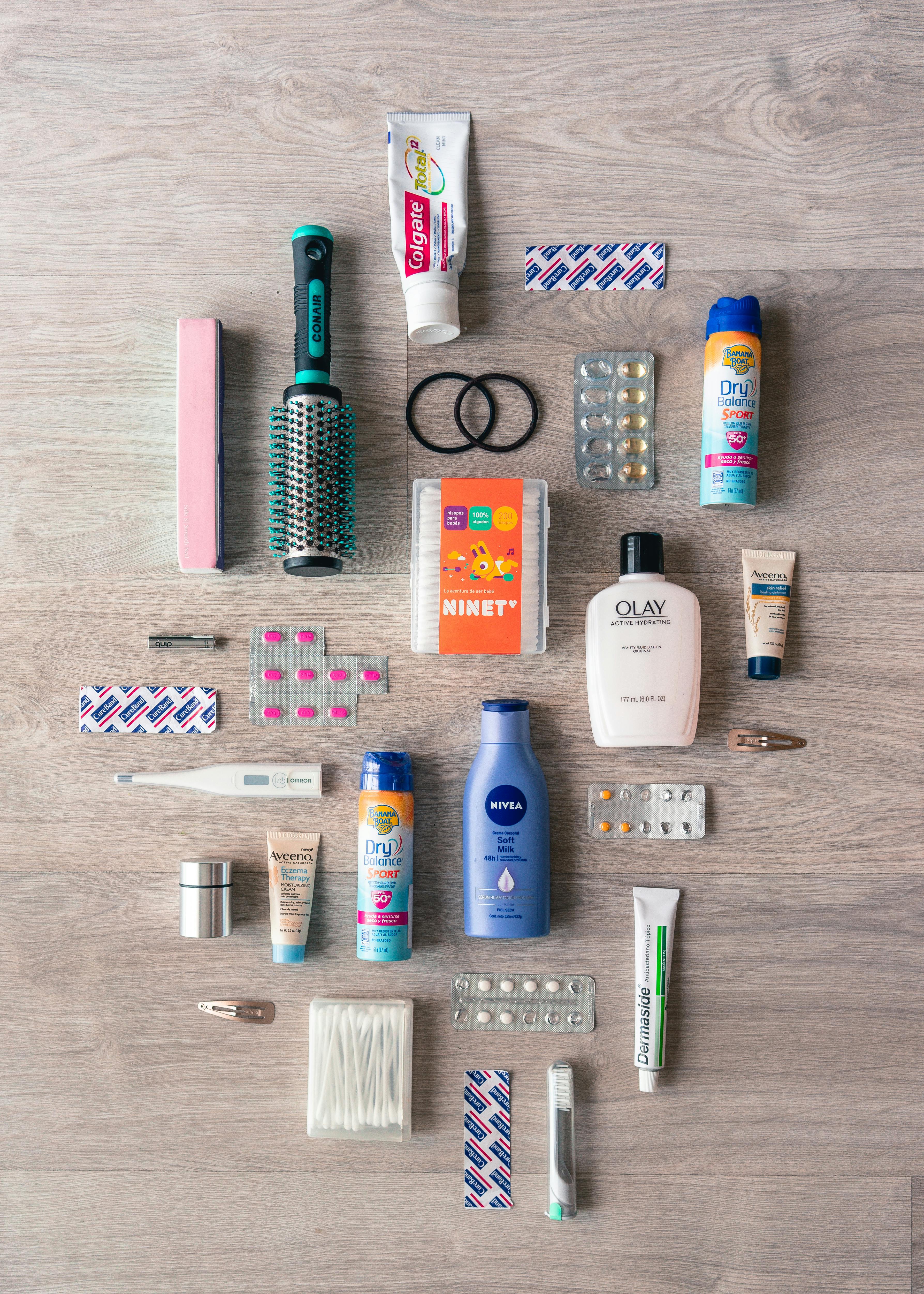 A neatly organized flat lay of toiletries and essentials including brushes, creams, and medicines.