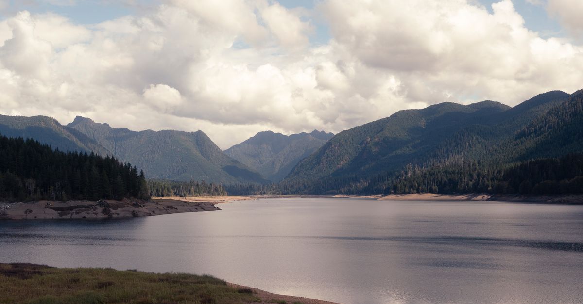 Tranquil mountain lake with lush evergreen forests and dramatic clouds in WA, USA.