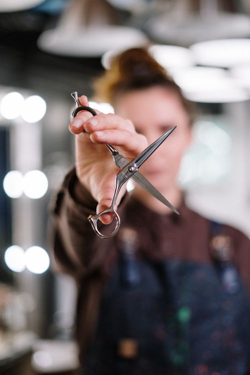 A woman looking in a mirror, considering a new hairstyle at a beauty salon