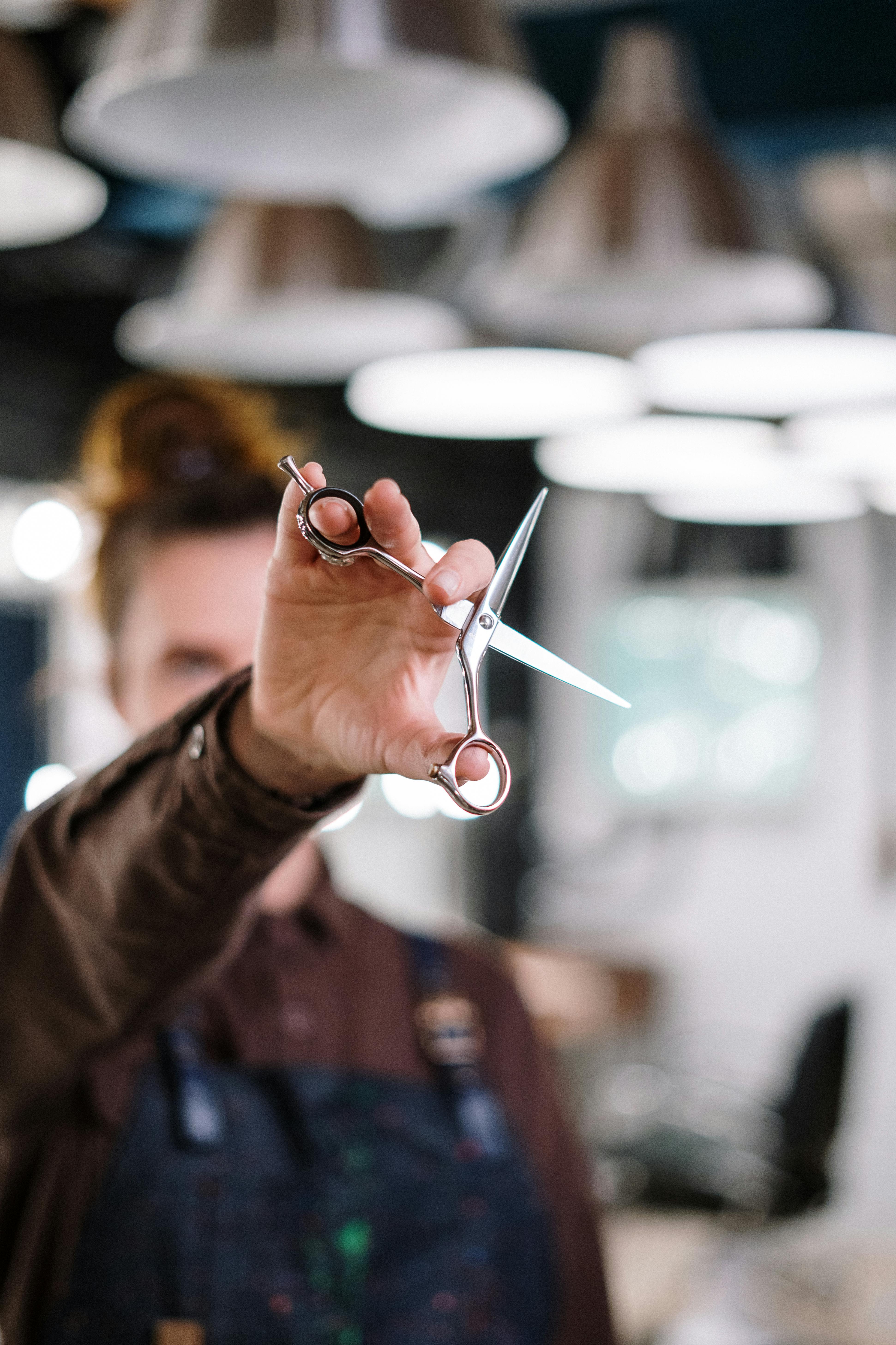 person in brown long sleeve shirt holding silver scissors