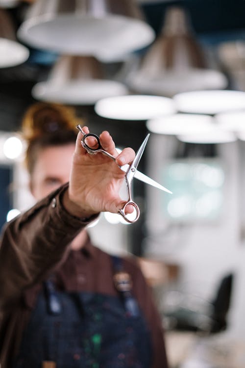 Person in Brown Long Sleeve Shirt Holding Silver Scissors