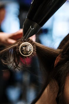 特写镜头中，发型师在沙龙里用刷子和烘干机为头发造型