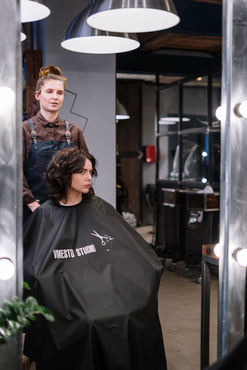 A professional hair stylist attending to a brunette client in a modern salon setting. Stylish environment.