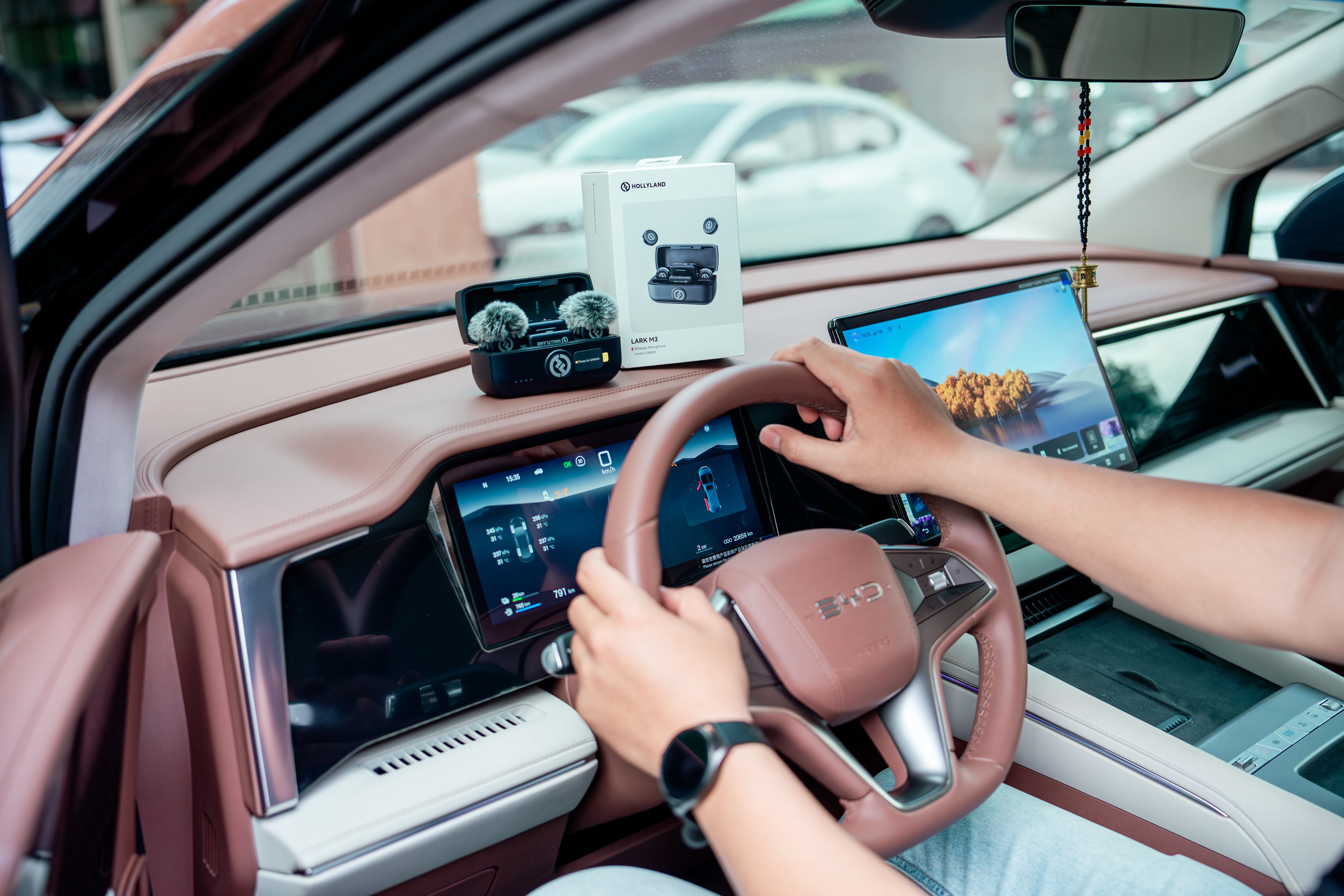Car interior with a person interacting with a dashboard featuring tech gadgets.