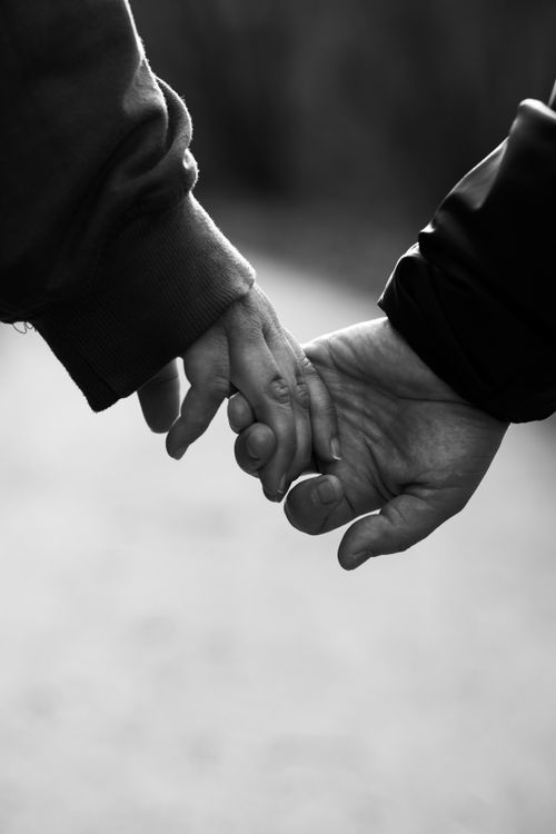 Free A touching black and white photo of two people holding hands outdoors. Stock Photo