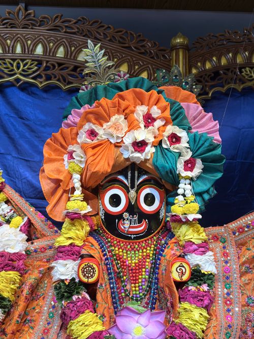 Free Vibrant Jagannath deity adorned with colorful flowers in traditional attire against a decorative backdrop. Stock Photo