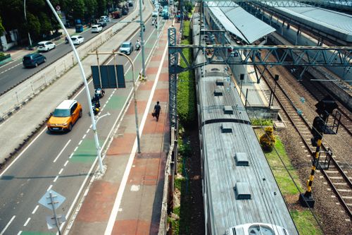 Free Aerial view of a busy street alongside a train station, capturing urban transport dynamics. Stock Photo
