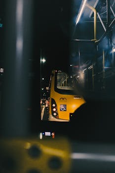 Illuminated yellow bus on a city street at night, showcasing urban transportation.