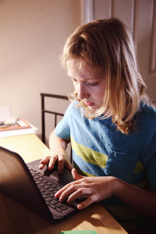Woman in Blue Crew Neck Shirt Using Black Laptop Computer