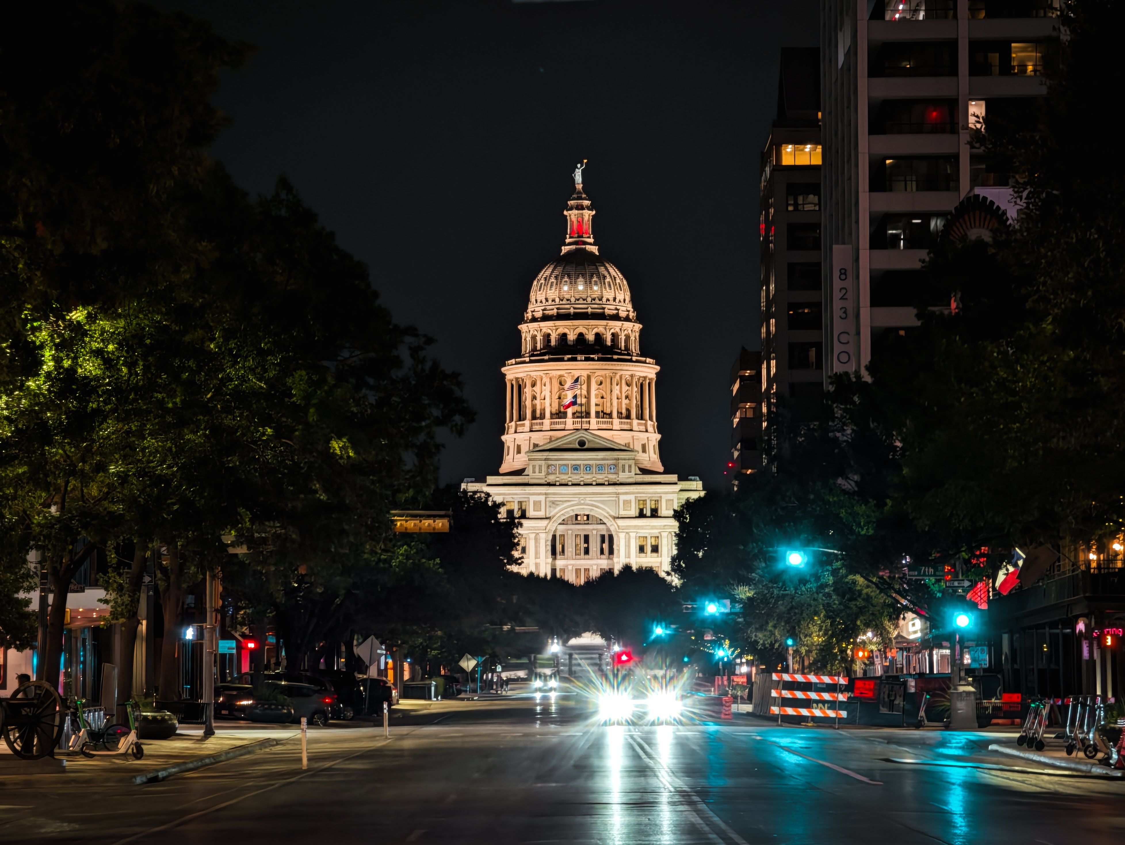 Night view of the illuminated Texas Capitol Building in Austin, captured from downtown street.