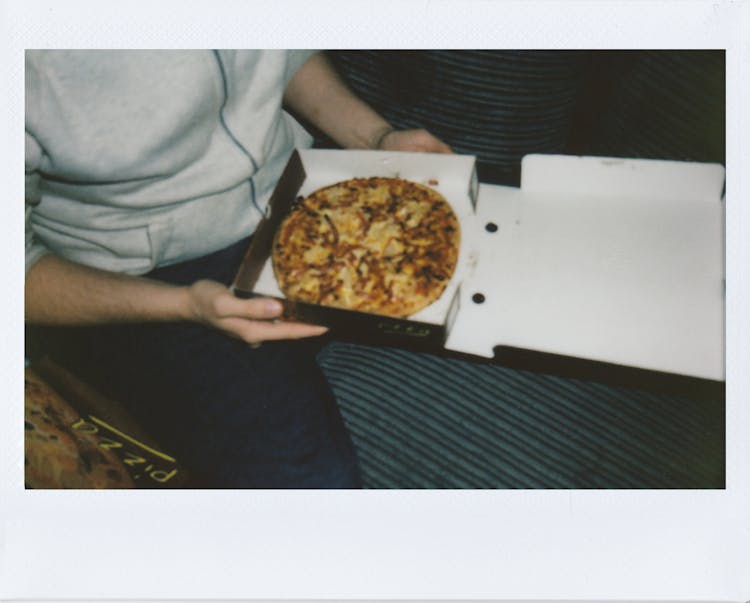 Person Sitting Holding A Box Of Pizza