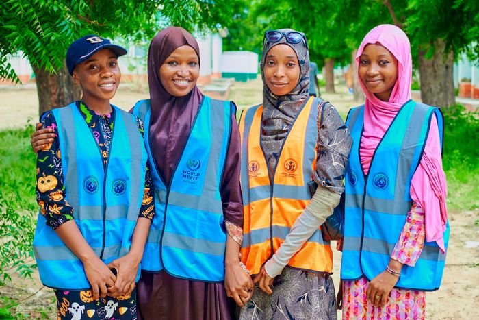 Quatre jeunes bénévoles souriants lors d'une action communautaire
