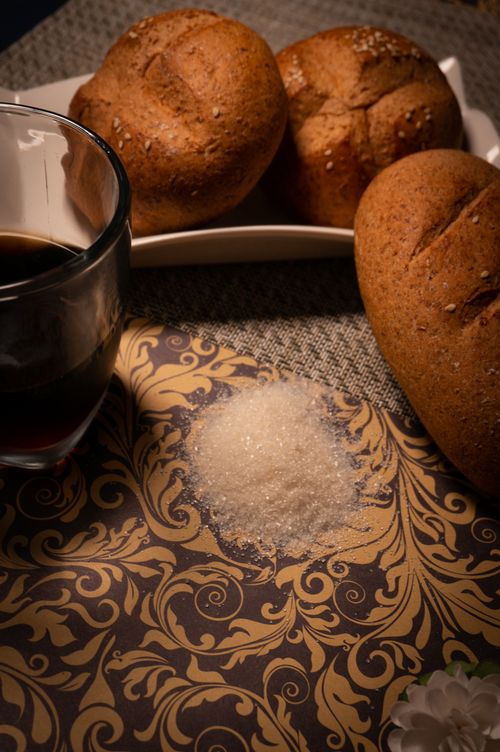 Free Rustic artisan bread with a cup of coffee on a patterned background, evoking a cozy café ambiance. Stock Photo