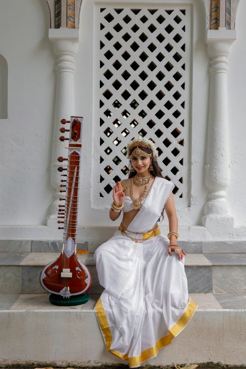 Free A woman dressed as a Hindu goddess poses with a sitar in a cultural photoshoot. Stock Photo