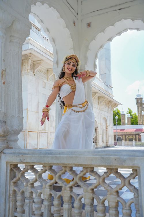 Free Indian woman in traditional attire performing classical dance at an ancient marble monument, embodying cultural heritage. Stock Photo