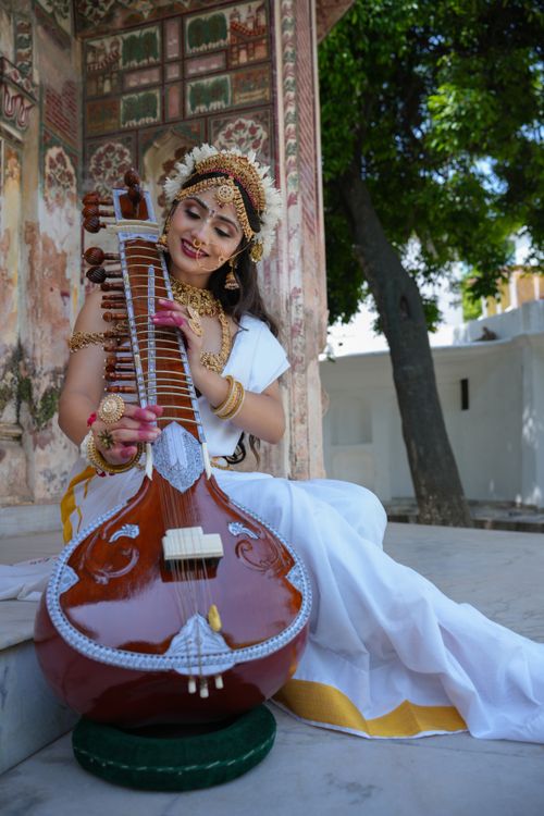 Free An Indian woman in traditional attire plays a veena in a culturally rich setting, embodying ethnic grace. Stock Photo