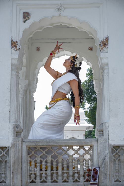 Free Capture of a woman in traditional attire performing a graceful dance pose in an ornate architectural setting. Stock Photo