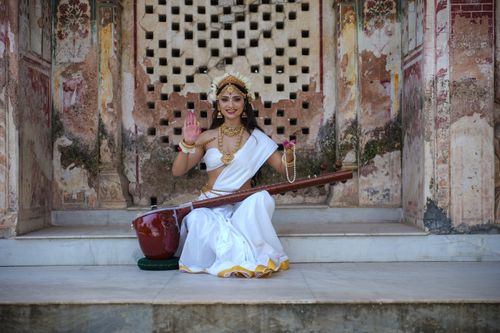 Free A woman in traditional Indian attire poses with a veena, showcasing classical dance in historic setting. Stock Photo