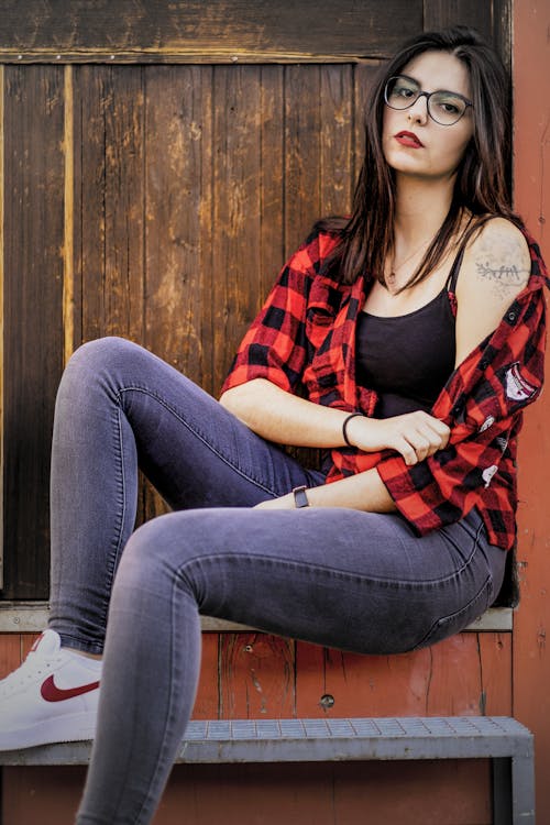 nul hagl måle Woman in Red and Black Plaid Shirt and Blue Denim Jeans Sitting on Brown  Wooden Bench · Free Stock Photo