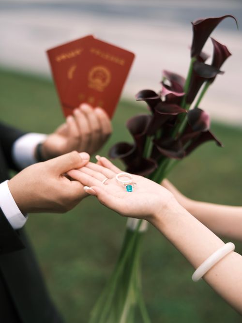 Free Close-up of hands exchanging rings with a bouquet, symbolizing engagement. Stock Photo