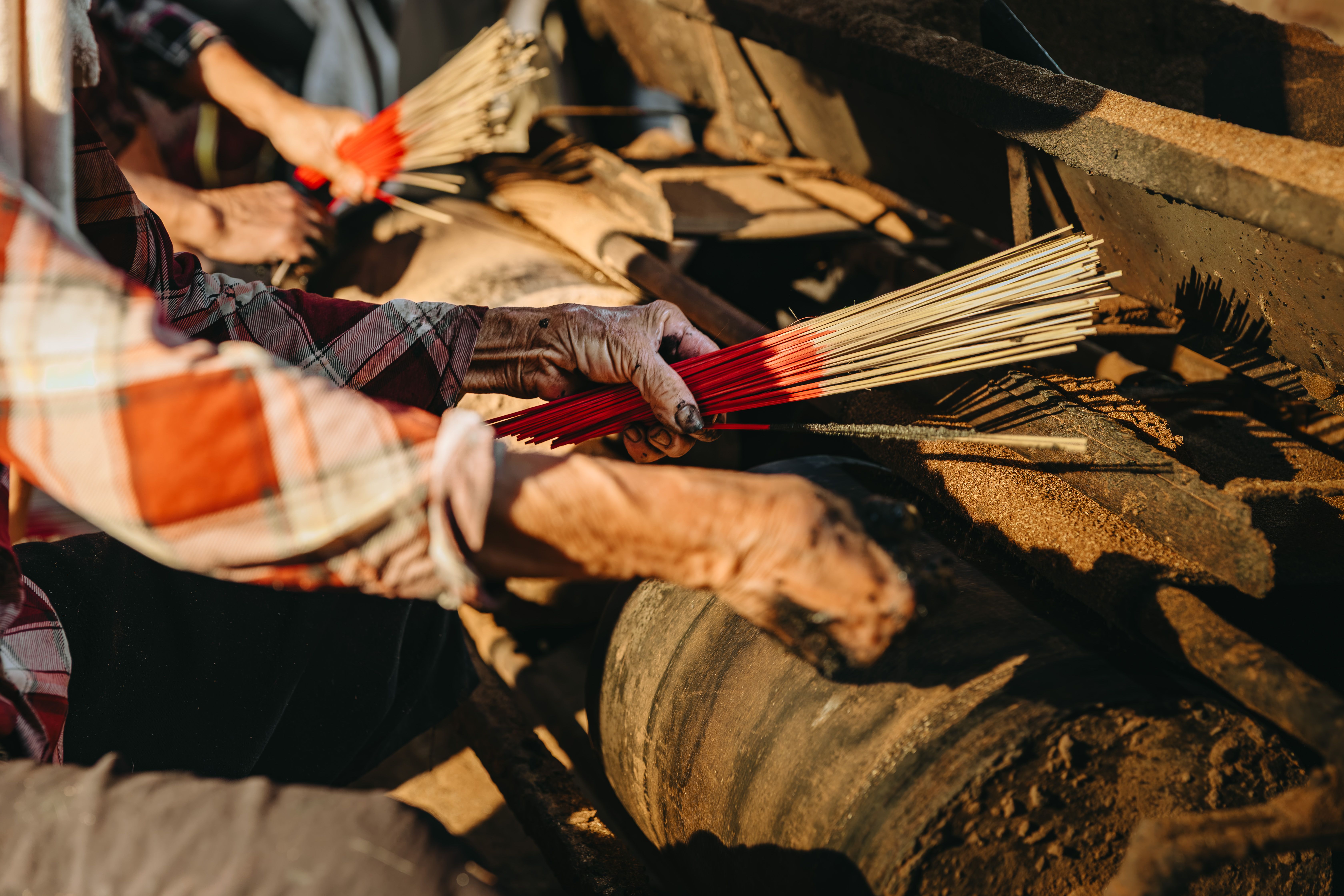 Close-up of skilled hands crafting traditional incense sticks in a workshop setting.