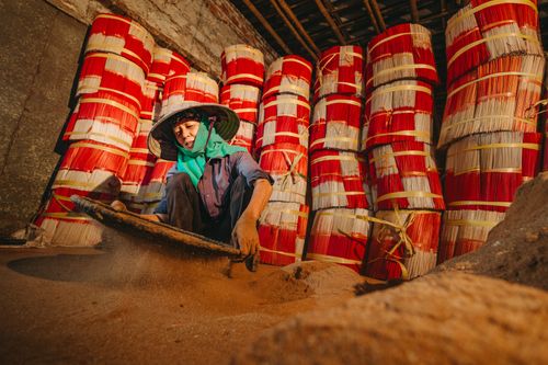 Free Person sifting sand for incense stick production at an indoor factory. Stock Photo