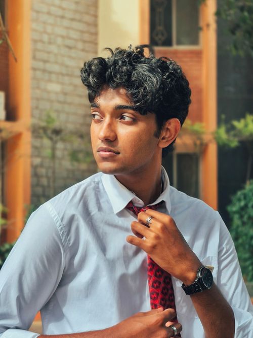 Free Portrait of a young man in formal attire adjusting his tie outdoors, exuding a thoughtful and professional demeanor. Stock Photo