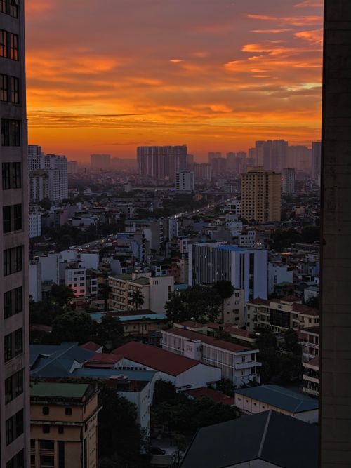 Free Urban skyline at sunset with vibrant orange hues over the city buildings. Stock Photo