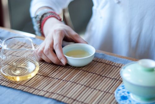Free A close-up shot of a hand holding a ceramic tea cup on a bamboo mat, creating a calming and relaxed mood. Stock Photo