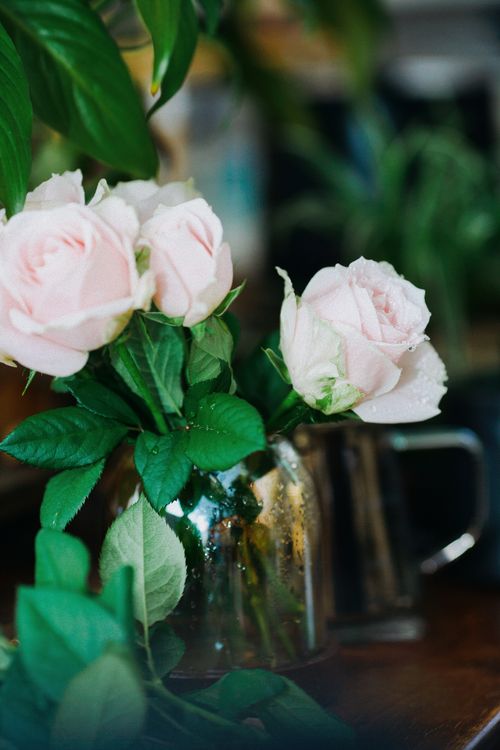 Free Elegant pink roses displayed in a rustic, reflective vase, showcasing a soft and natural aesthetic. Stock Photo