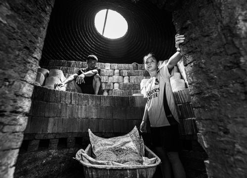 Free Captivating black and white image of two people in a traditional pottery workshop. Stock Photo