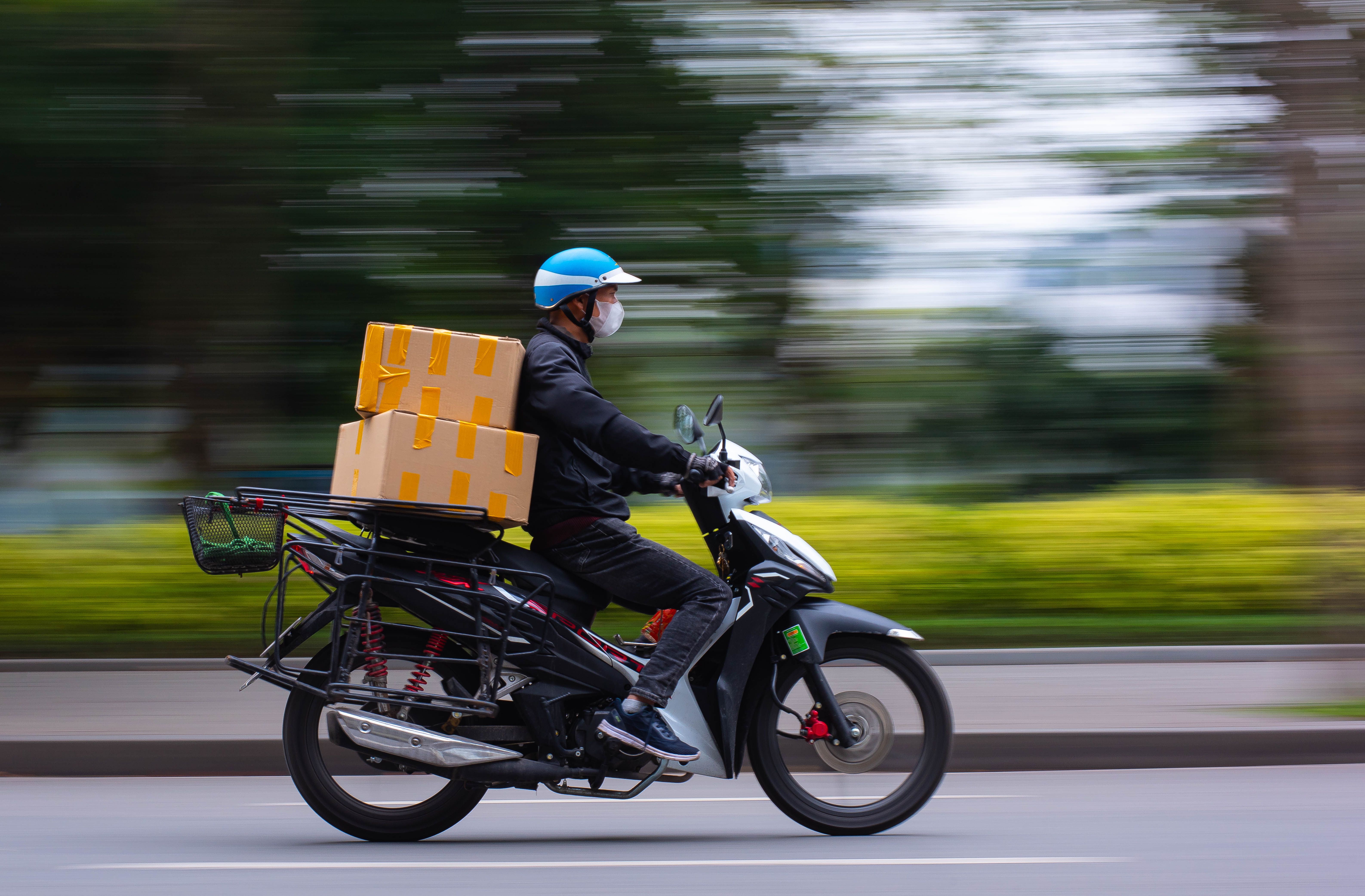 Fast-paced delivery service on a scooter in urban setting, capturing motion and speed.