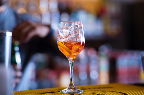 Free Close-up of a refreshing Aperol Spritz cocktail with ice and orange slice on a bar counter, perfect for summer enjoyment. Stock Photo