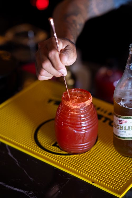 Free Close-up of a hand stirring a spicy michelada on a bar mat. Stock Photo