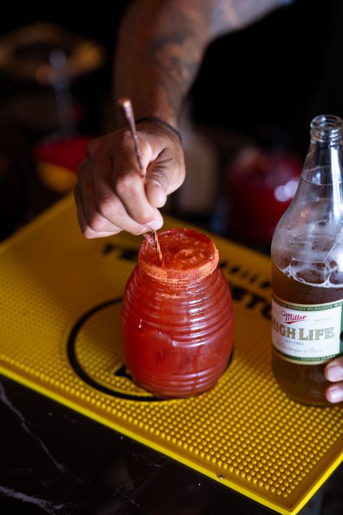 Free Close-up of a hand stirring a refreshing michelada with beer and spicy tomato juice in a bar setting. Stock Photo