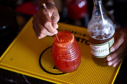 Free Close-up of crafting a michelada with spicy rim and beer at a bar, highlighting drink preparation. Stock Photo