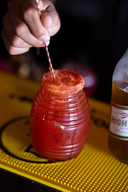 Free Close-up of a hand stirring a michelada cocktail, showcasing vibrant colors and fresh ingredients. Stock Photo